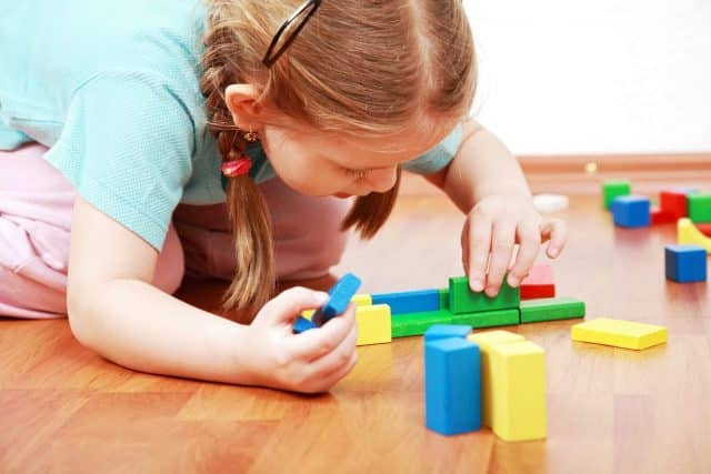 Young girl playing with colourful building blocks.