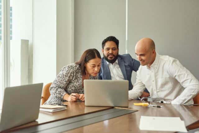 Image of three diverse university tutors looking at a laptop.