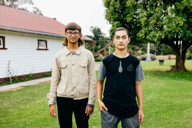 Image of two young Maori boys standing on a marae