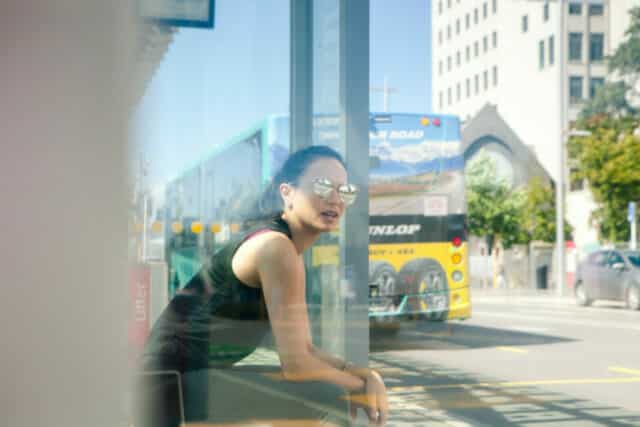Image of female student waiting at a bus stop