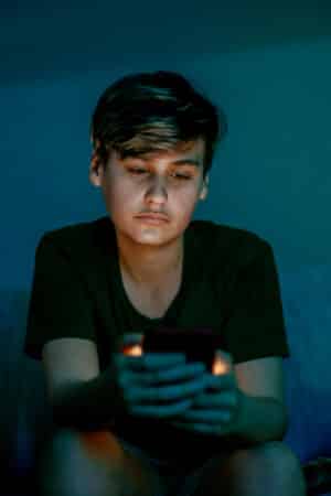 Image of student on their phone in the dark