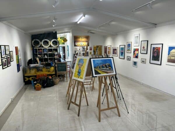 A gallery space with pictures and paintings on easels and on the wall. 